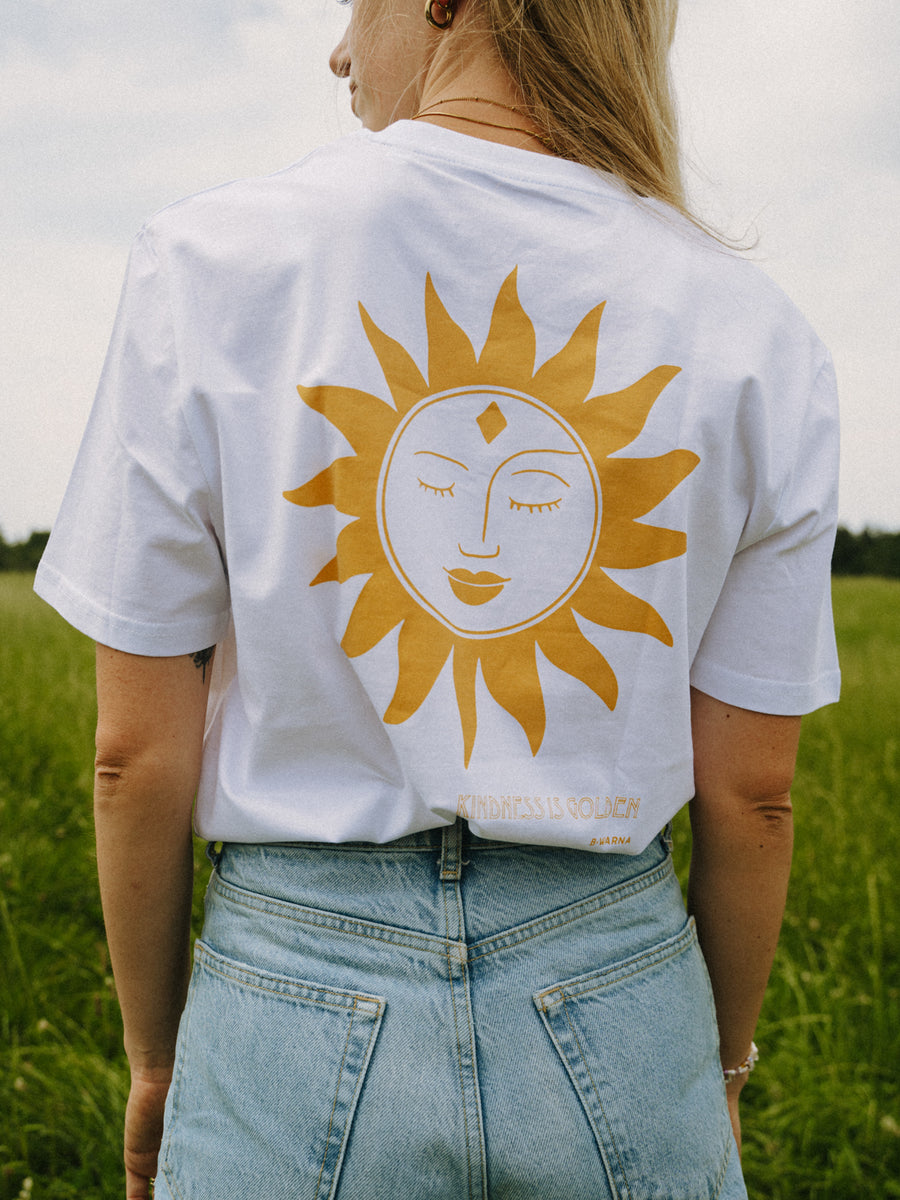 Frau trägt das KINDNESS T-Shirt in Weiß von hinten – große gelbe Sonne mit geschlossenen Augen, handbedruckt im Siebdruck