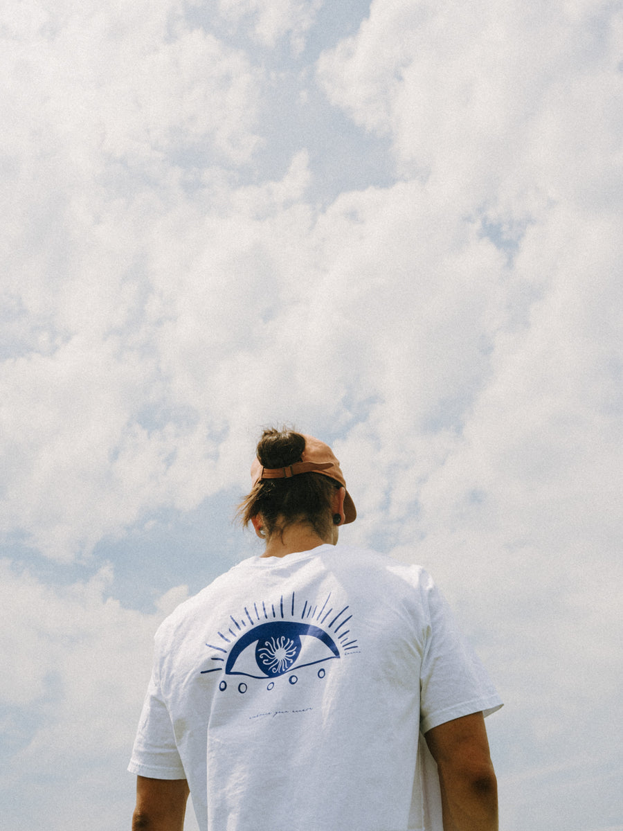 Mann trägt das EMBRACE T-Shirt in Weiß von hinten – großes blaues Auge-Motiv auf dem Rücken, handbedruckt im Siebdruck
